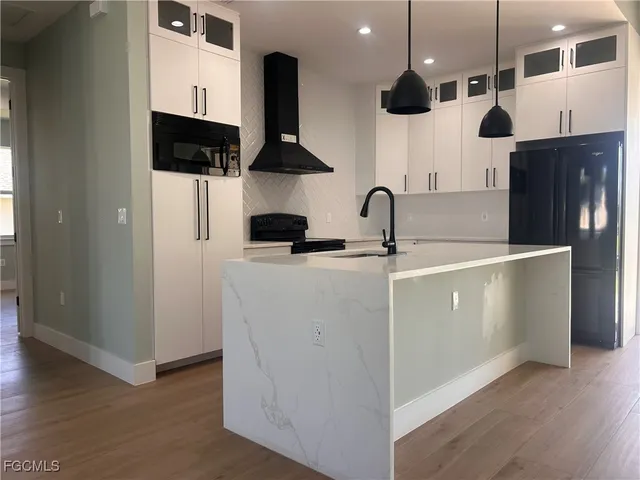 a kitchen with stainless steel appliances a sink a refrigerator and wooden floor