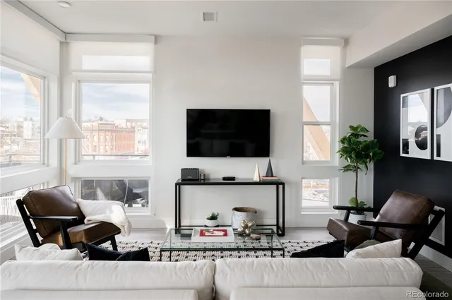 a living room with furniture a flat screen tv and a large window