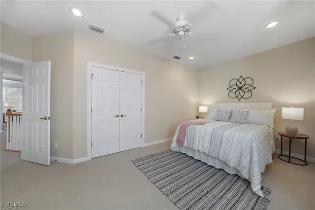 a spacious bedroom with a bed and lamp on desk