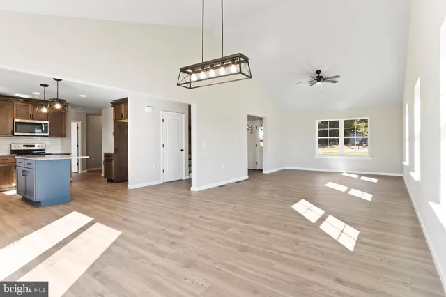 a view of an empty room with kitchen and window
