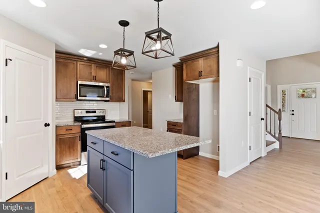 a kitchen with stainless steel appliances granite countertop a refrigerator a stove top oven a sink dishwasher and a refrigerator with wooden floor