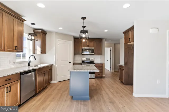a large kitchen with stainless steel appliances lots of counter space sink refrigerator and cabinets