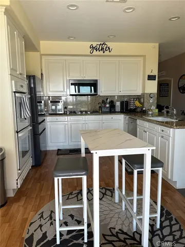 a kitchen with stainless steel appliances granite countertop a stove top oven a sink and a refrigerator