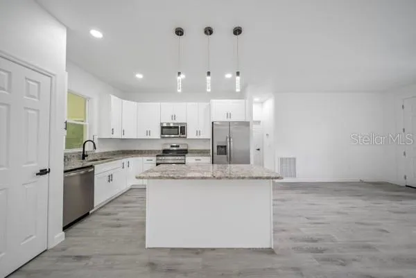a large white kitchen with kitchen island a sink stainless steel appliances and a counter top