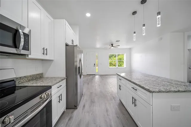 a kitchen with stainless steel appliances granite countertop a stove a sink and a microwave
