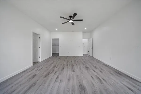 an empty room with wooden floor a ceiling fan and staircase
