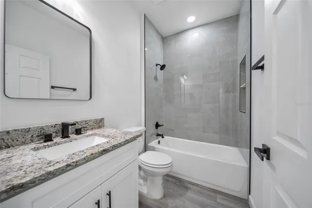 a bathroom with a granite countertop sink toilet a large mirror a bathtub and shower