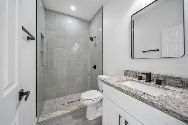 a bathroom with a granite countertop sink a toilet and a shower