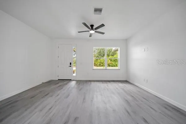 an empty room with a window and a ceiling fan