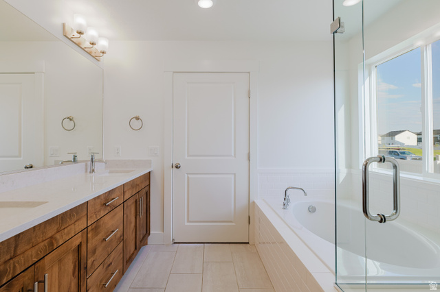 433 North 600 West Smithfield, UT 84335 - Photo 36 of 40 Bathroom featuring a dual vanity with wood-finish cabinetry, a large frameless mirror, and a built-in bathtub with a white tile surround