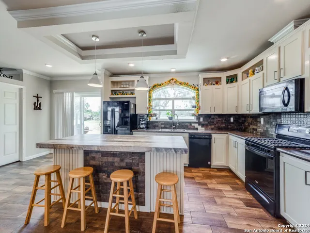 a kitchen with stainless steel appliances granite countertop a stove top oven a sink a dining table and chairs