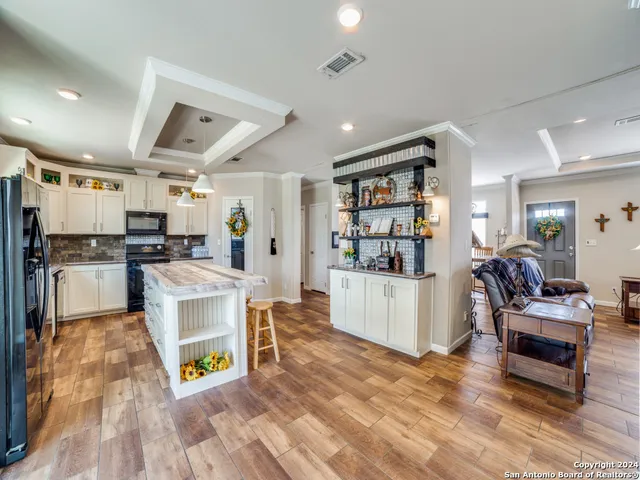 a living room with stainless steel appliances kitchen island granite countertop furniture and a wooden floor