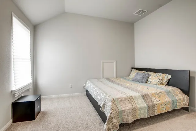 a large bed sitting in a bedroom next to a window