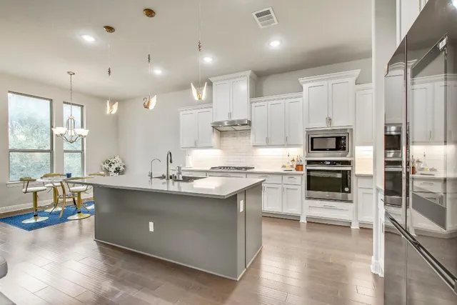 a kitchen with stainless steel appliances kitchen island granite countertop a stove top oven a sink and a refrigerator