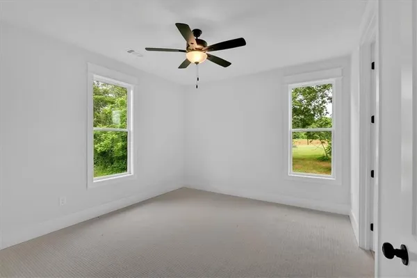 an empty room with windows and ceiling fan