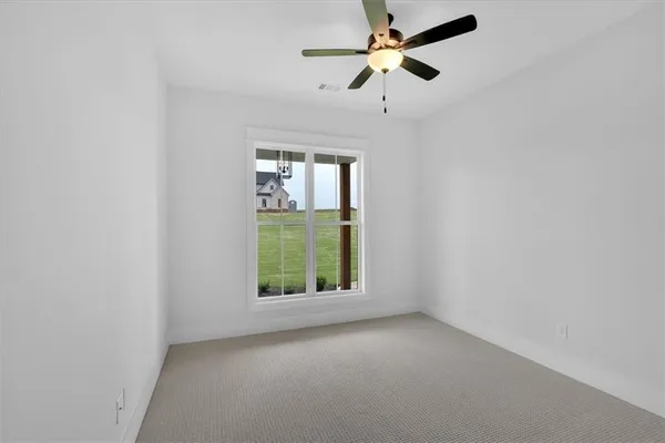 an empty room with windows and fan