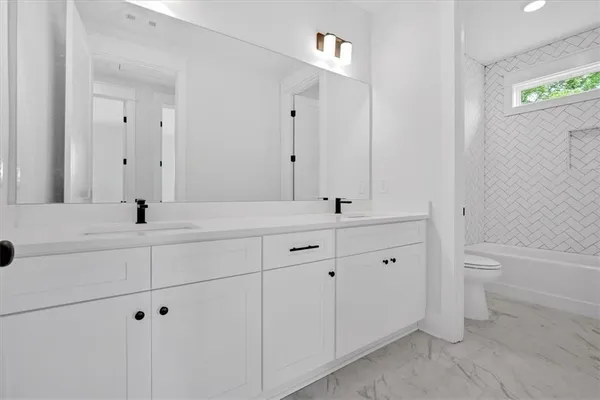 a bathroom with a double vanity sink a toilet and a bathtub