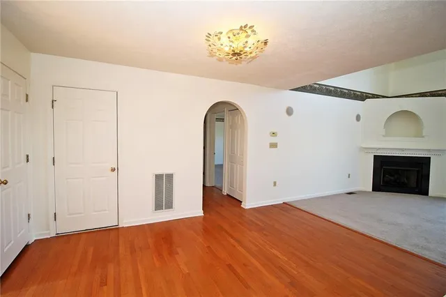 a view of empty room with wooden floor and fireplace