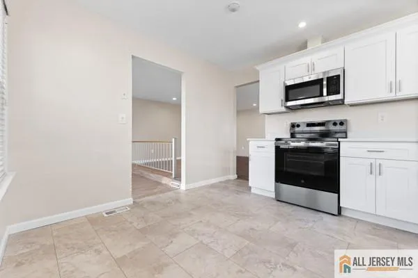 a kitchen with granite countertop white cabinets and stainless steel appliances