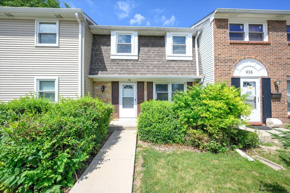 a view of a brick house with a yard and potted plants