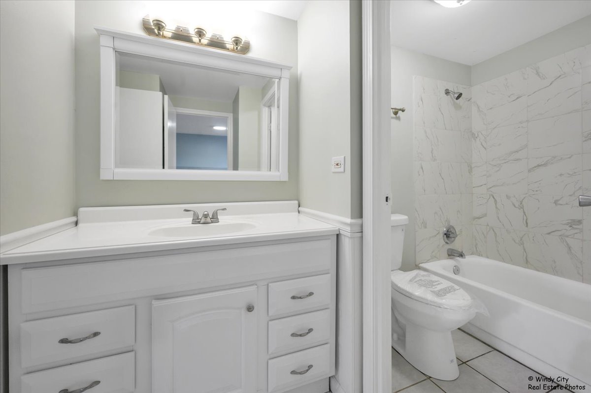 936 Cardiff Court Schaumburg, IL 60169 - Photo 18 of 35 a bathroom with a granite countertop sink a toilet and a bathtub