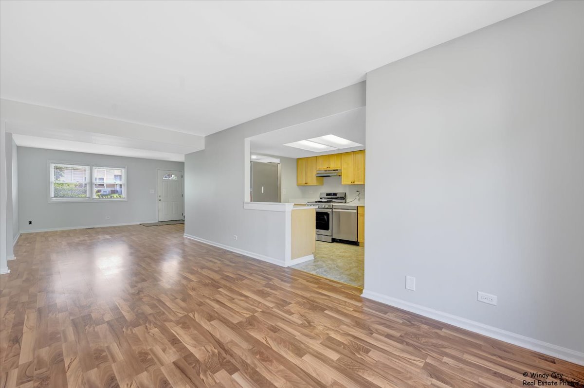 936 Cardiff Court Schaumburg, IL 60169 - Photo 5 of 35 a view of a kitchen and an empty room with wooden floor