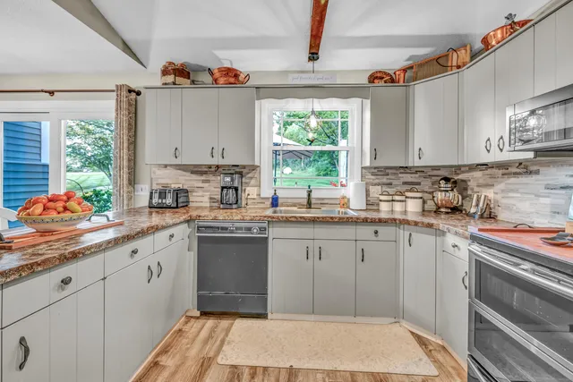 a kitchen with kitchen island granite countertop a sink window and cabinets
