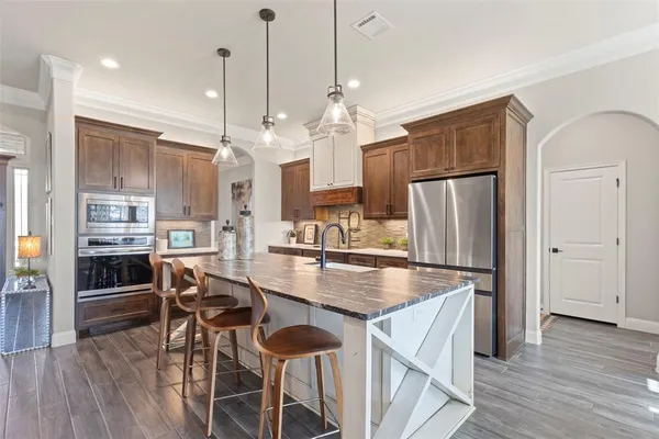 a kitchen with stainless steel appliances granite countertop a refrigerator a stove and a wooden floors