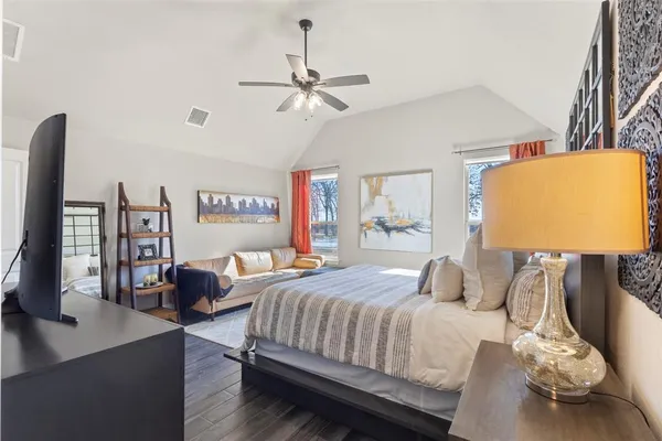 a bedroom with a bed a couch and a flat tv screen on the dresser