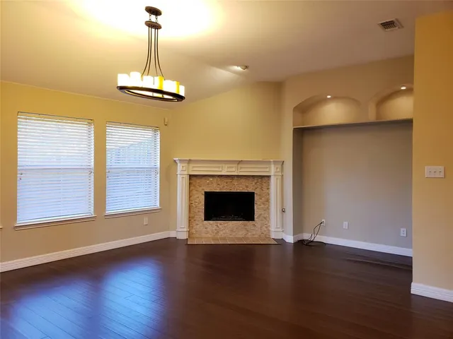 an empty room with wooden floor fireplace and windows