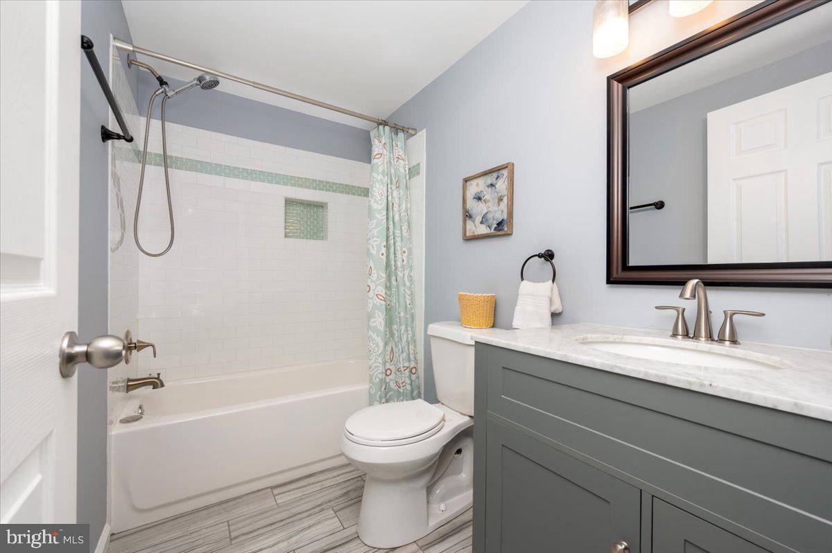 7804 East A E Shore Road Pasadena, MD 21122 - Photo 23 of 34 a bathroom with a granite countertop sink toilet a mirror and shower