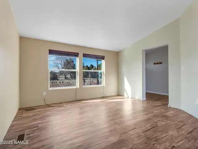 a view of an empty room with window and wooden floor