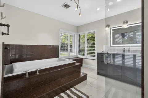 a bathroom with a bathtub a mirror and a shower