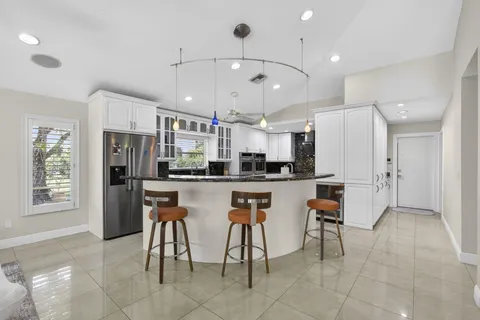 a large white kitchen with a large window a sink and stainless steel appliances