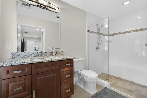 a bathroom with a granite countertop bathtub shower and toilet