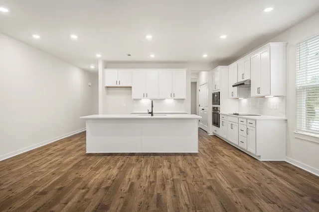 a large kitchen with stainless steel appliances granite countertop a lot of counter space and wooden floors