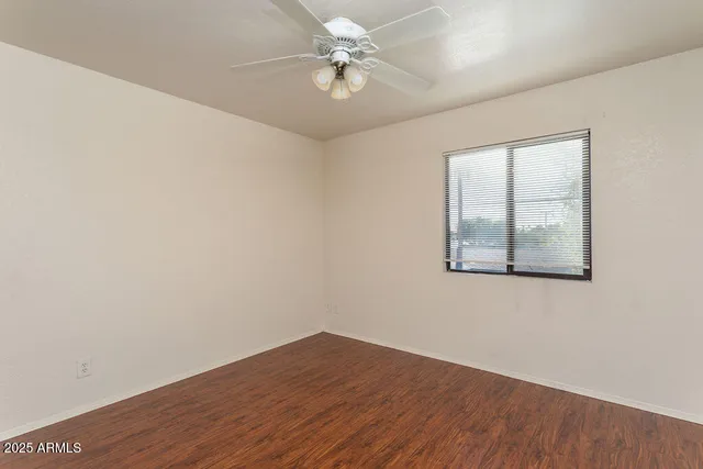 an empty room with a window and a ceiling fan