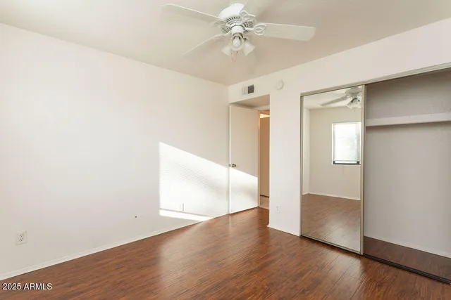 an empty room with wooden floor and ceiling fan