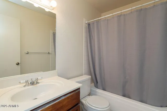 a bathroom with a sink a toilet a mirror and shower curtain