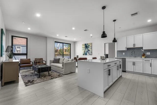 a kitchen with stainless steel appliances kitchen island granite countertop a dining table chairs and a refrigerator