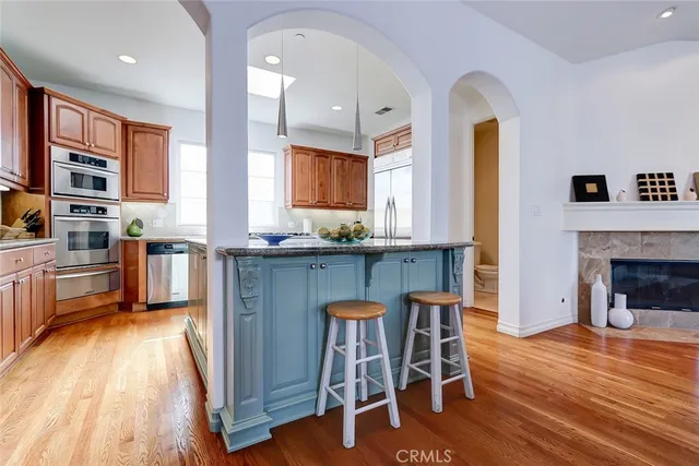 a kitchen with stainless steel appliances granite countertop a stove top oven a sink dishwasher a dining table and chairs with wooden floor