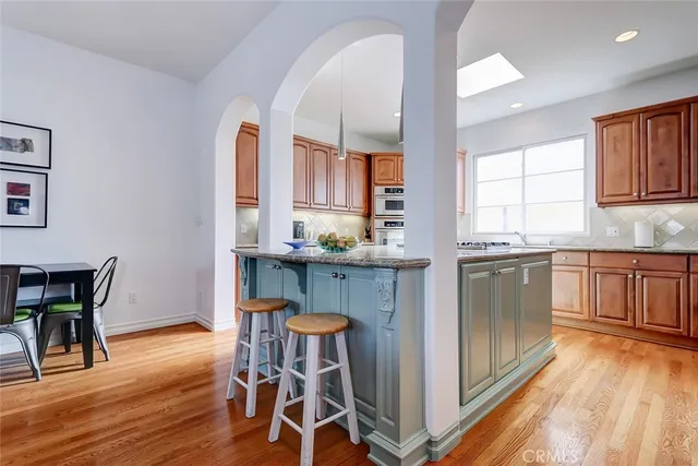 a kitchen with stainless steel appliances granite countertop wooden floor and white cabinets