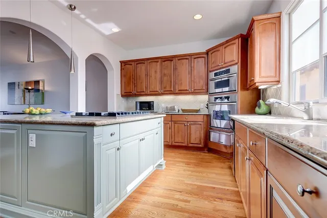 a kitchen with stainless steel appliances granite countertop a sink a stove cabinets counter space and a window