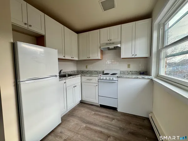 a kitchen with cabinets appliances a sink and a window