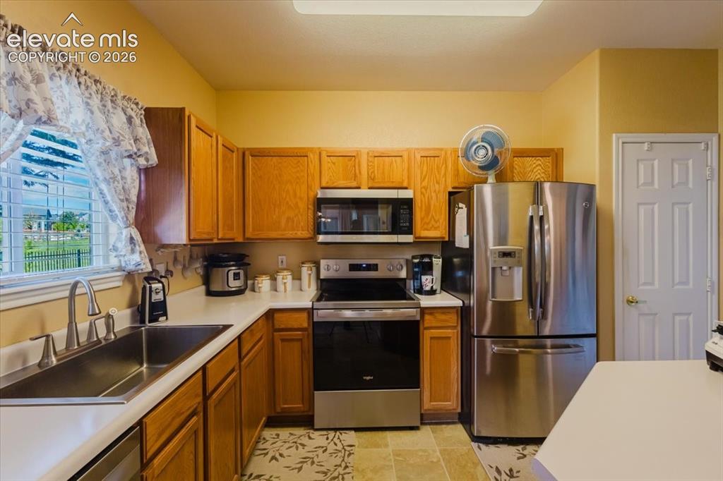 4008 Riviera Grove, Unit 103 Colorado Springs, CO 80922 - Photo 6 of 39 Gleaming stainless grace the kitchen along with the huge open sink. Notice the pantry door to the right of the fridge.