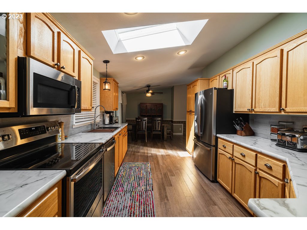 369 Gun Club Road, Unit 16 Woodland, WA 98674 - Photo 15 of 44 a kitchen with stainless steel appliances granite countertop a stove top oven a sink dishwasher a refrigerator and a dining table with wooden floor