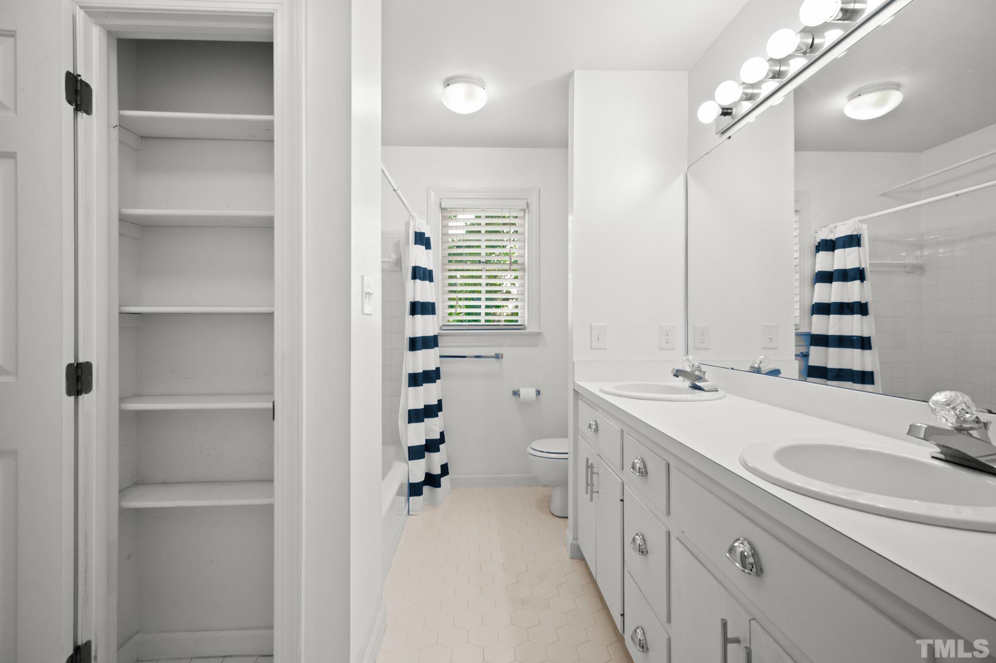1205 Weldon Place Raleigh, NC 27608 - Photo 31 of 33 a bathroom with a double vanity sink a mirror a shower and a bathtub