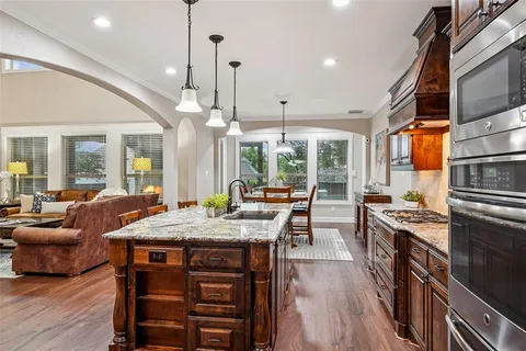 a kitchen with stainless steel appliances granite countertop a stove a sink dishwasher and a dining table with chairs