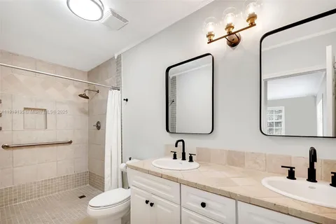 a bathroom with a double vanity sink toilet mirror and shower