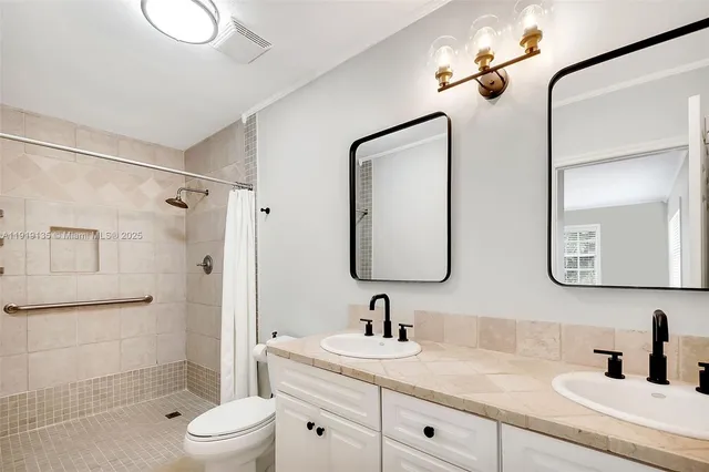 a bathroom with a double vanity sink toilet mirror and shower